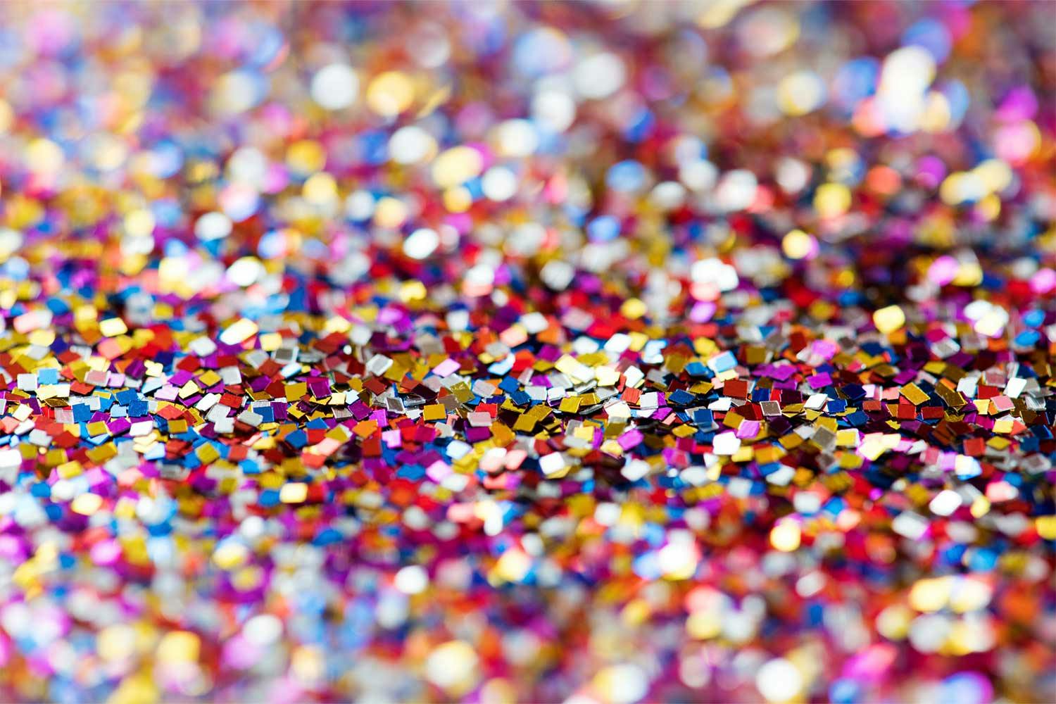A pile of tiny, square, shiny flecks of glitter in shades of red, gold, blue, and pink.