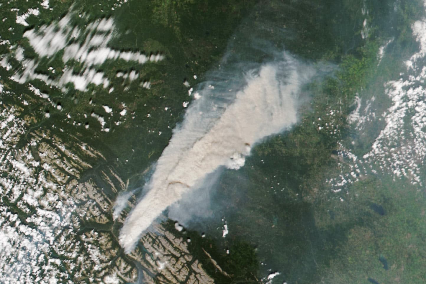 Satellite image of a thick grey plume of smoke from the Jasper wildfire complex rising bottom left to top right of frame.