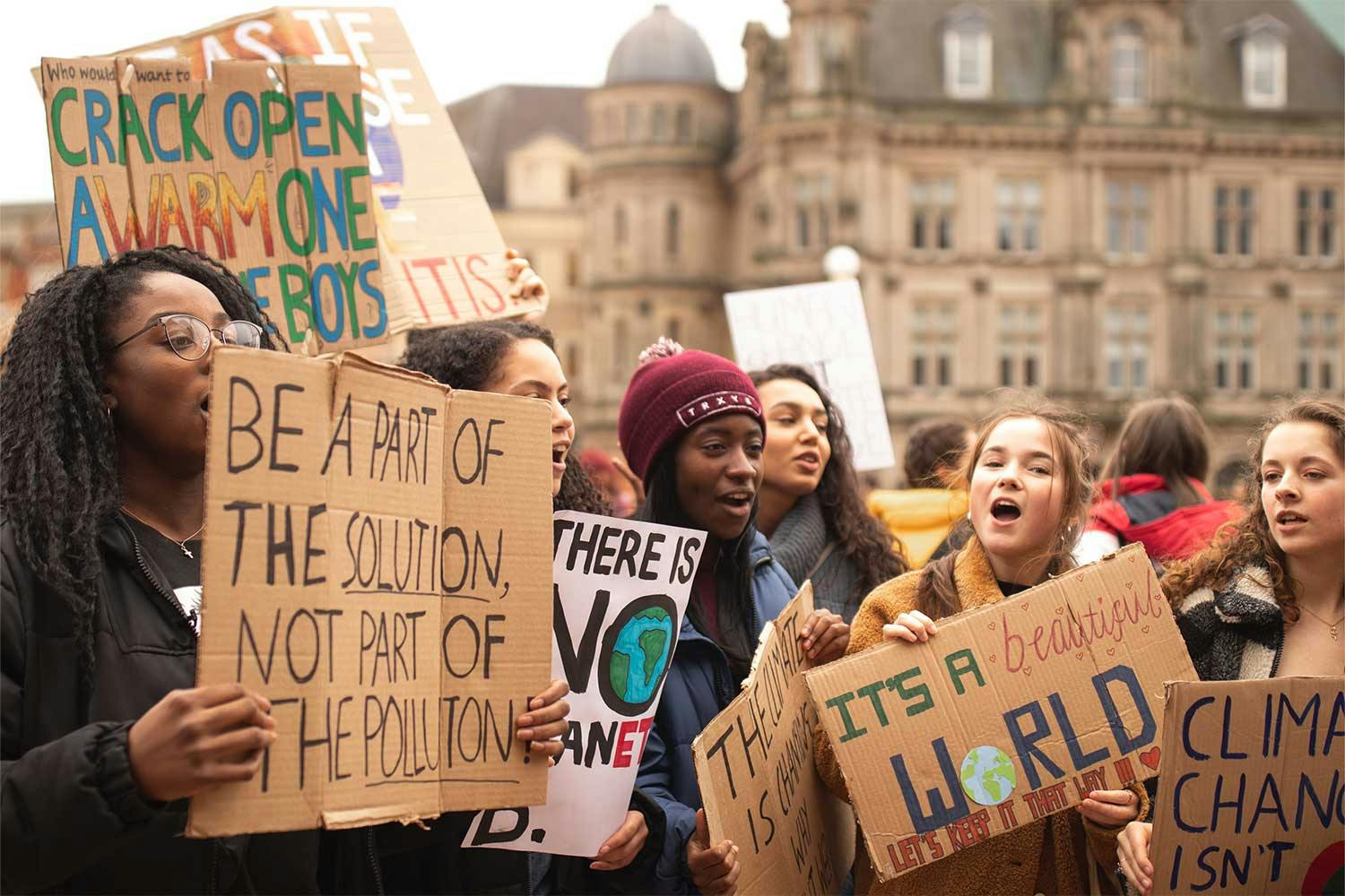 A group of young women holding cardboard signs bearing climate change-related slogans.