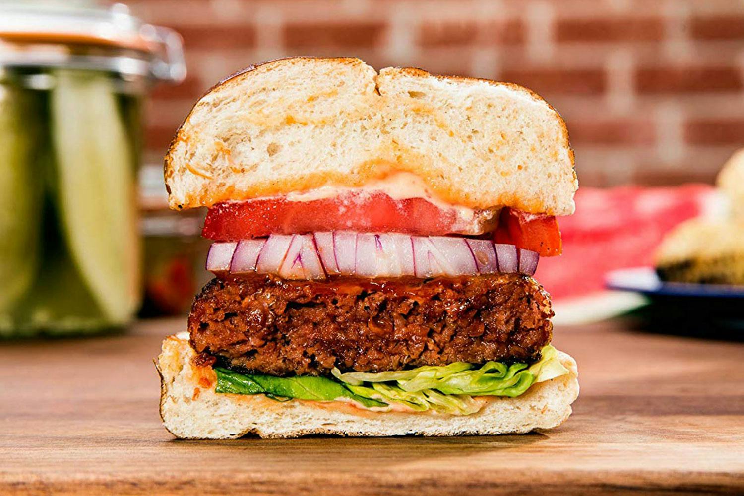 A burger made with a Beyond Meat plant-based patty cut in half to show a cross section with tomato, onion, and lettuce.