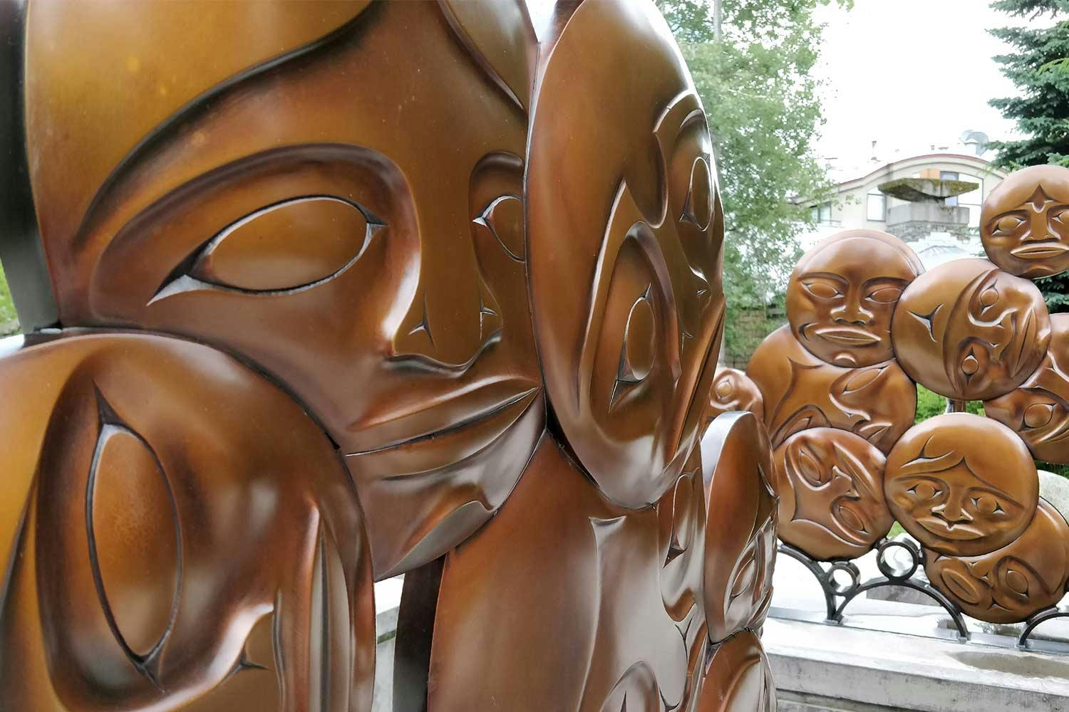A bronze sculpture in the Northwest Coast style of circular faces overlapping each other in Whistler, BC.