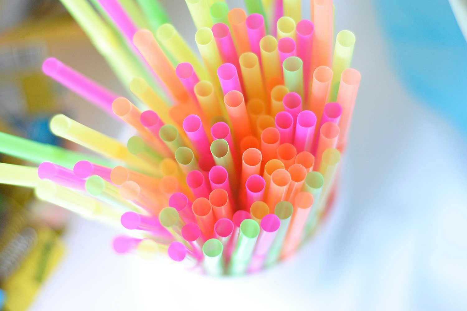 A bundle of bright pink, green, yellow, and orange plastic straws.