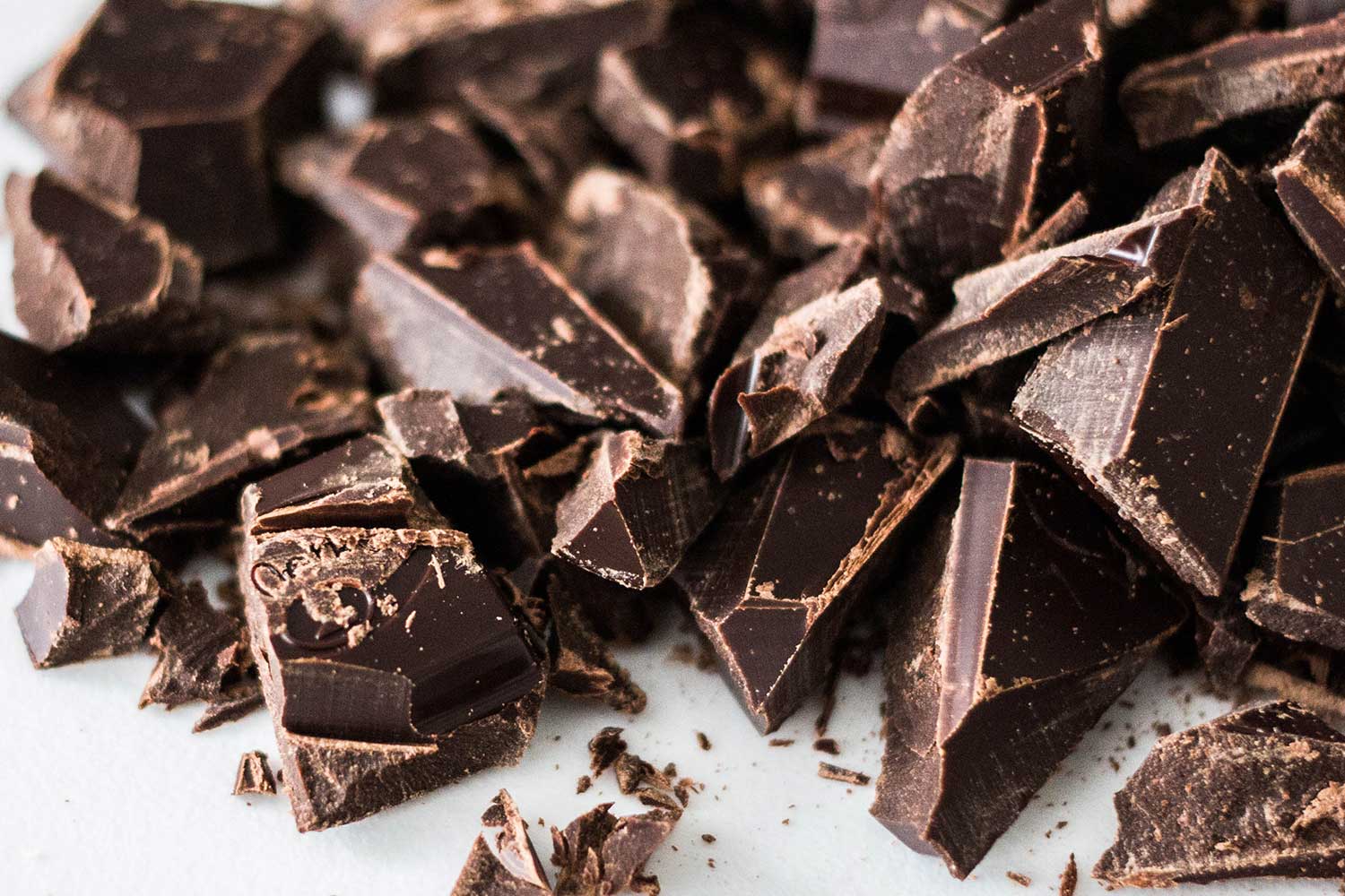 Jagged chunks of chocolate on a white surface.