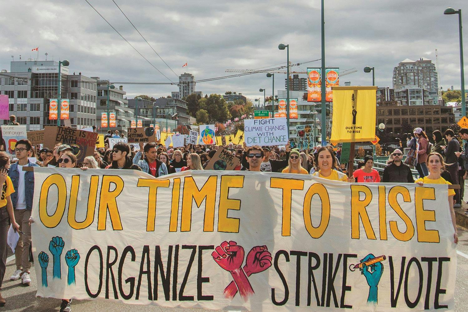 Activists lead a crowd across Vancouver’s Cambie Bridge with a banner that says “Our time to rise. Organize, Strike, Vote.”