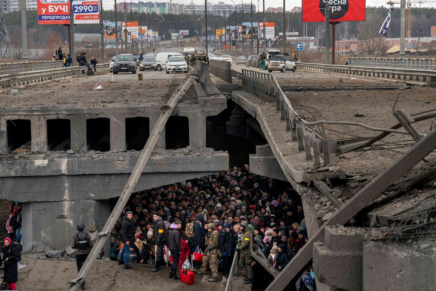 A crowd of Ukrainians take shelter under a damaged concrete bridge during the Russo-Ukrainian War.