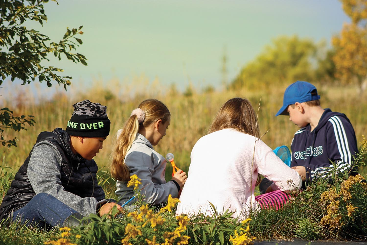 Four children sit in the grass of the Le Semoir orchard.