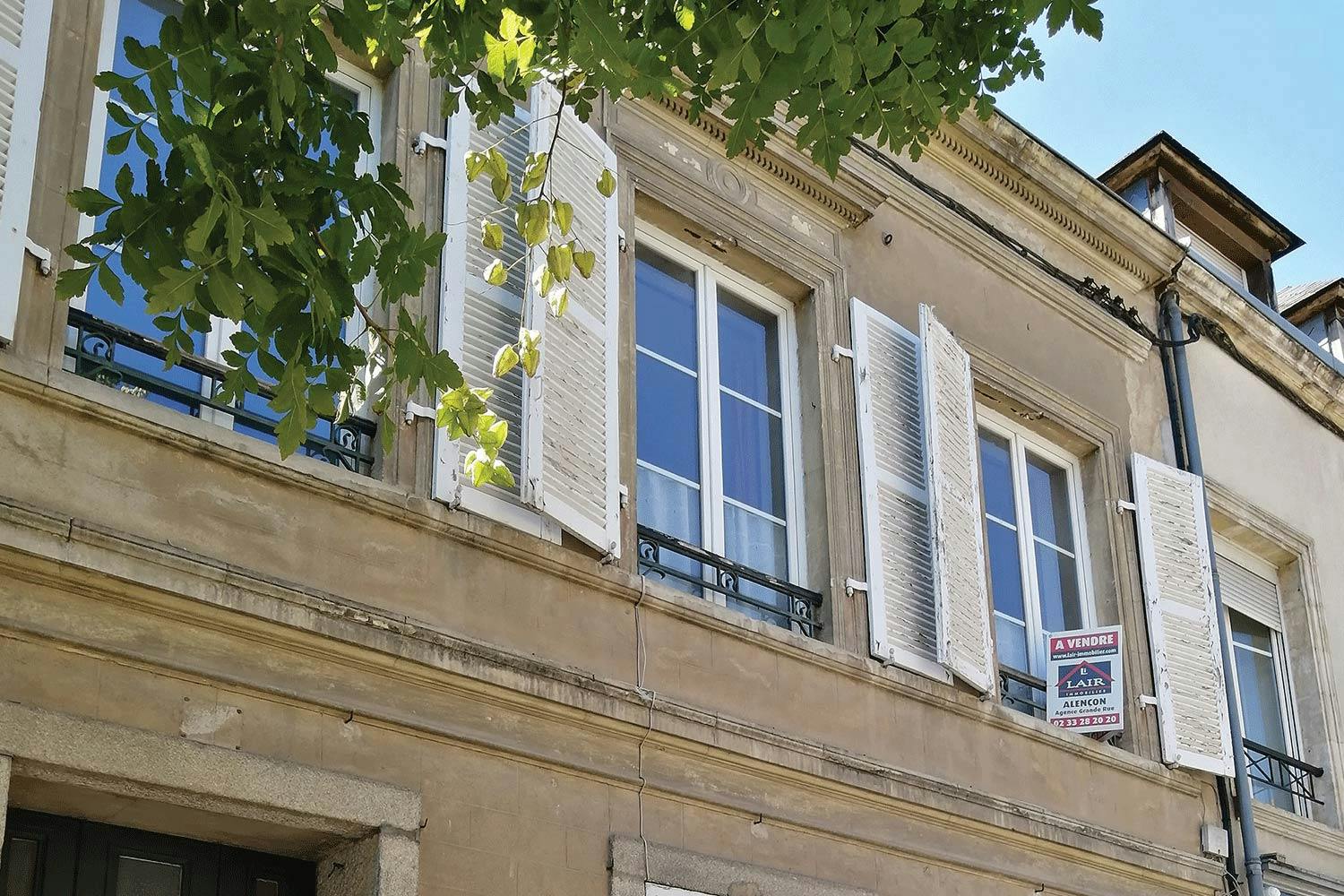 The exterior of a French apartment building with row of windows fitted with external shutters on either side of each window.