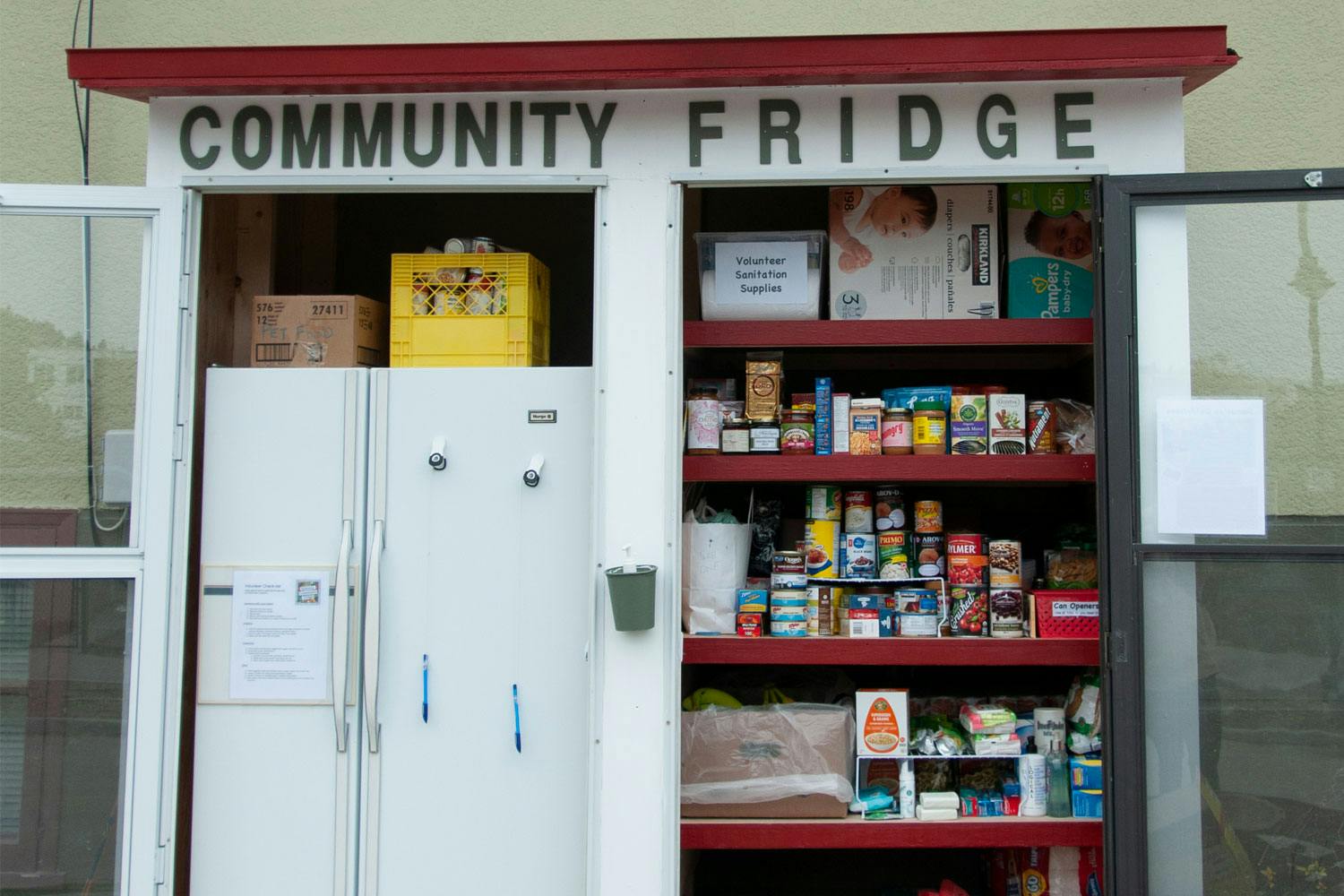 A small outdoor pantry with doors opened to show to a fridge and a shelf of canned goods.